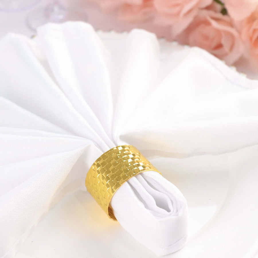 Gold woven napkin ring with white napkin elegantly arranged on a table.