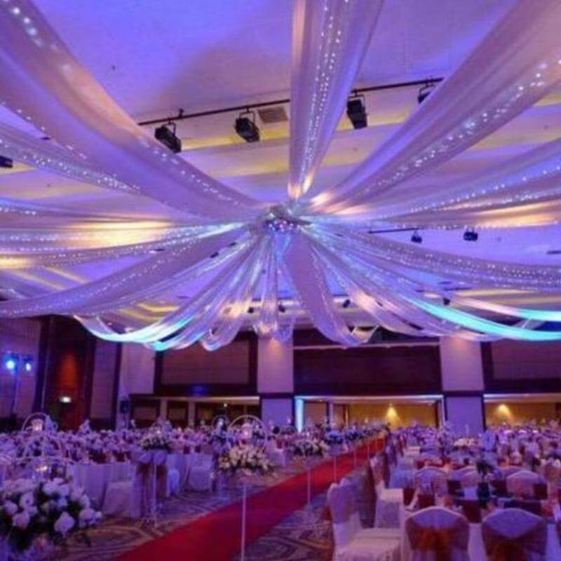 Elegant wedding reception decor with draped fabric and ambient lighting.