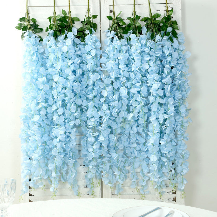 Blue artificial flower garlands hanging against a white background.