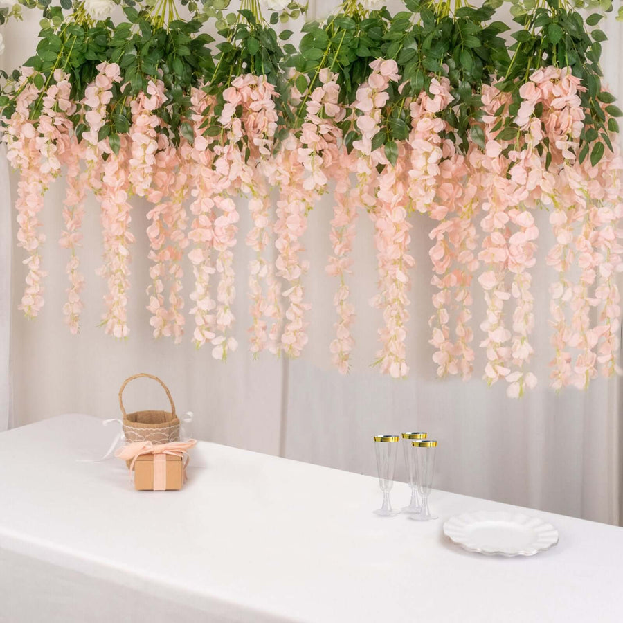 Pink floral garland hanging over a table with decorative items and glassware.