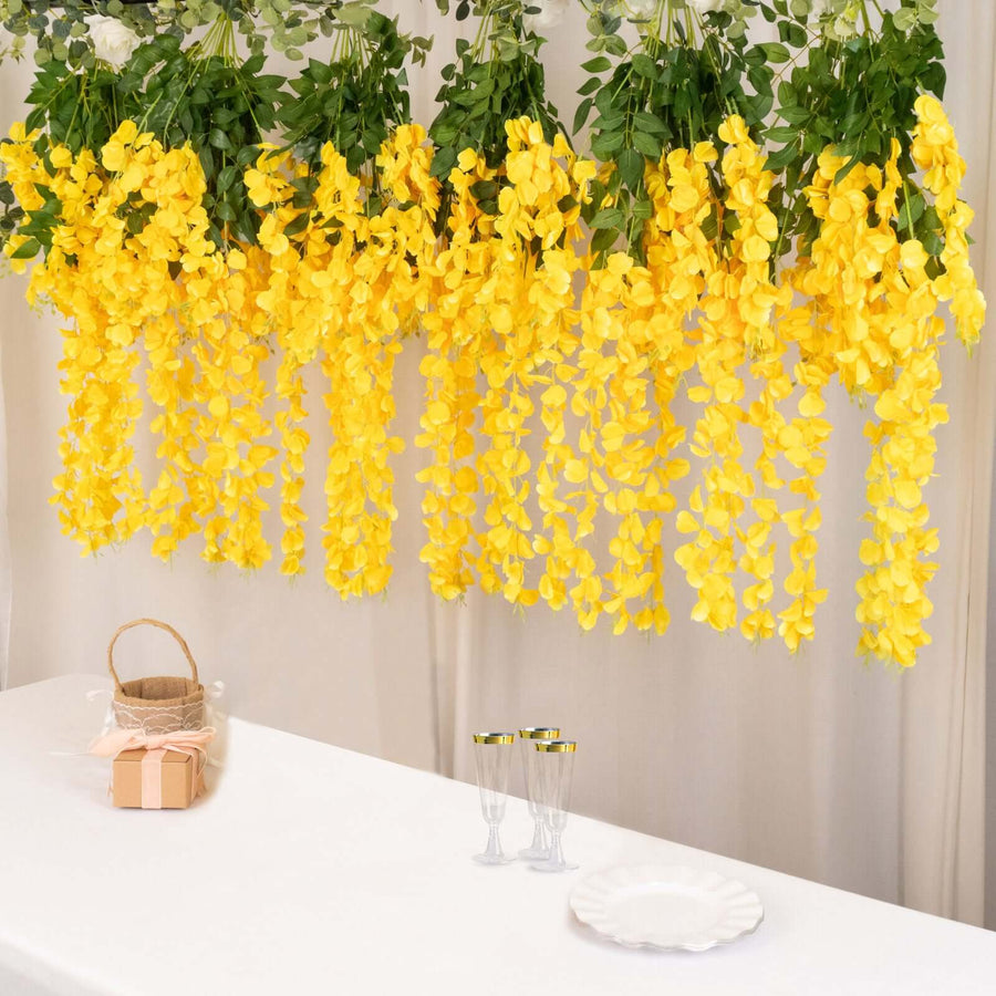 Artificial yellow flower garland hanging above a table with glasses and a basket.