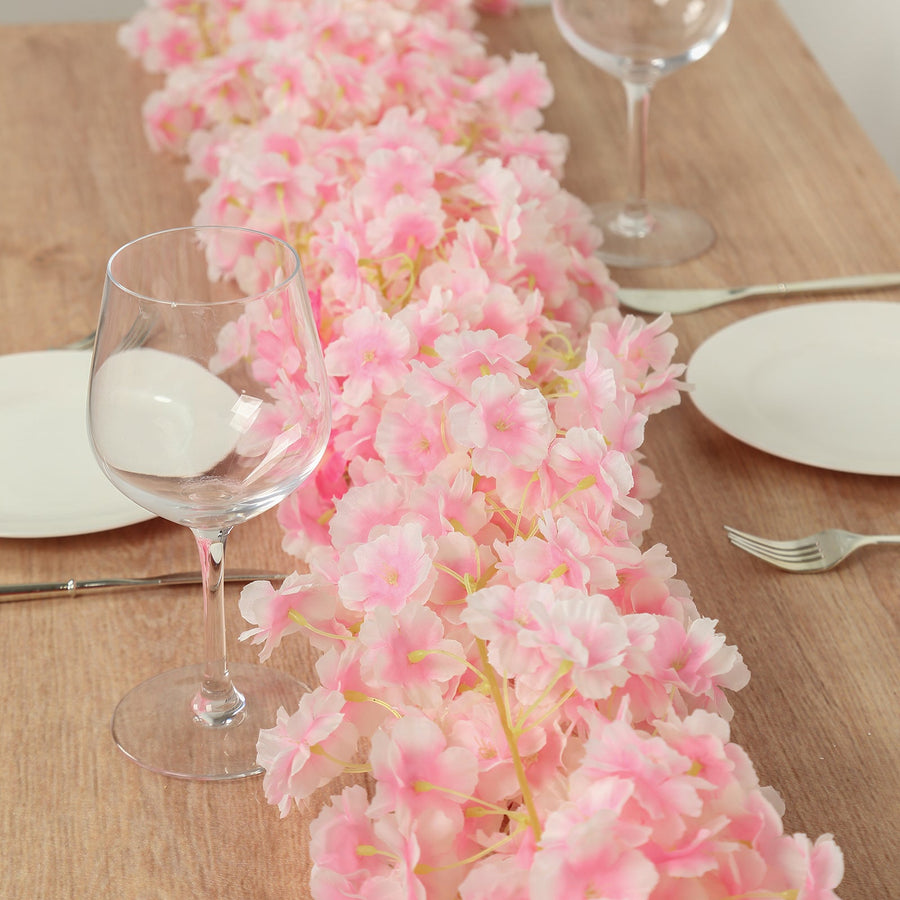 Pink floral table runner with wine glasses on a wooden table.