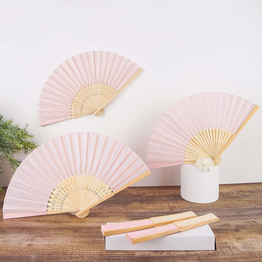 Pink folding fans displayed elegantly on a wooden surface.