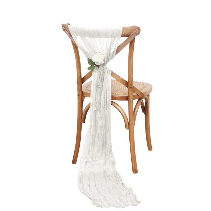 White decorative scarf draped on a wooden chair with a flower accent.