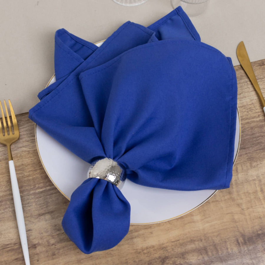 Blue napkins elegantly styled on a plate with a silver napkin ring.