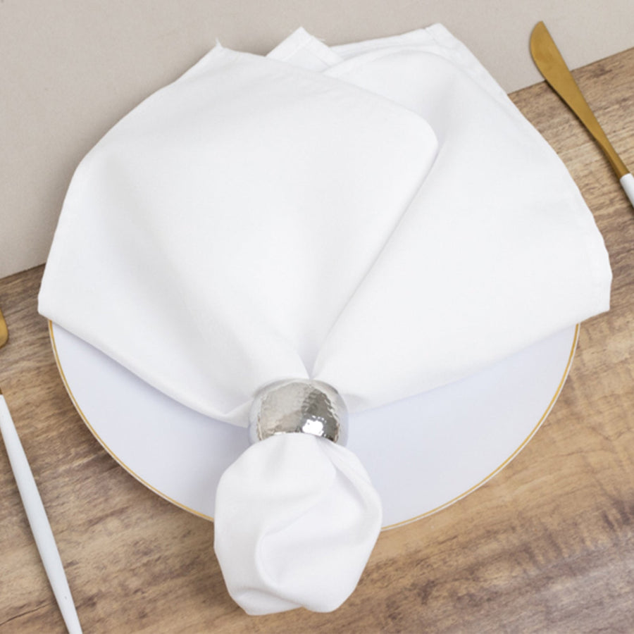 White napkin elegantly arranged on a plate with a silver napkin ring.