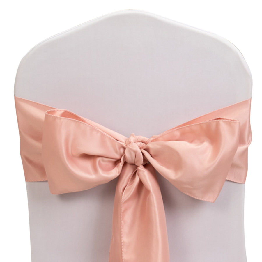 Pink satin chair sash tied in a bow on a white chair.