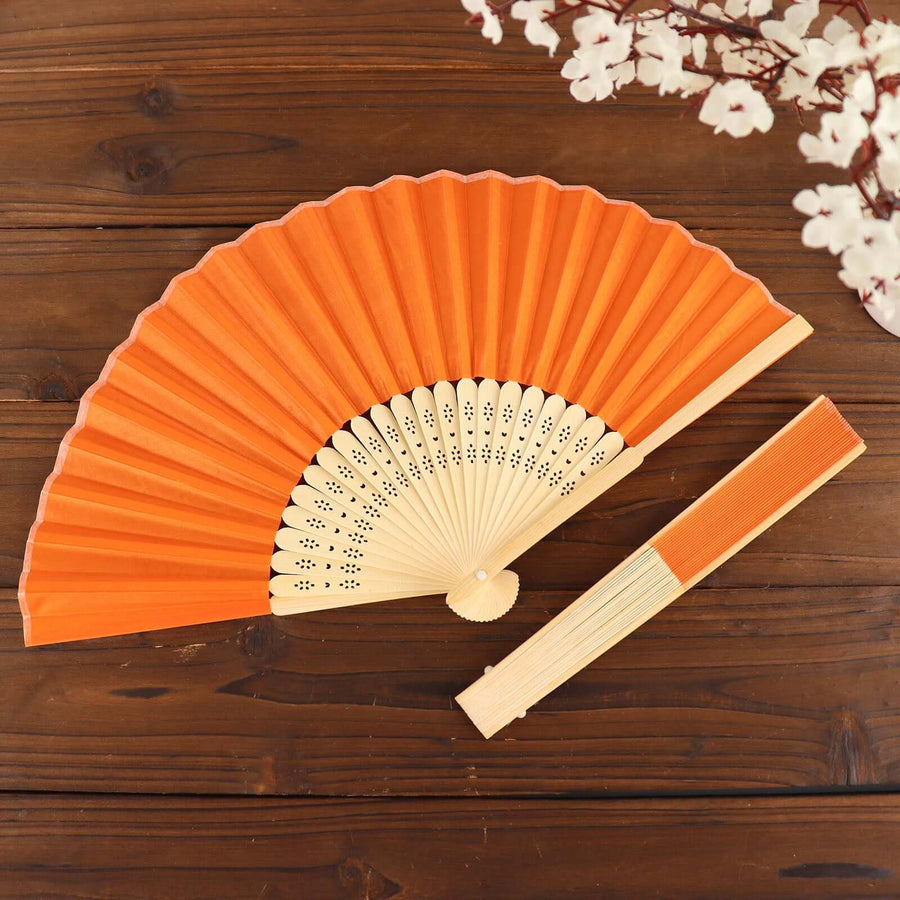 Orange decorative folding fan on a wooden surface.