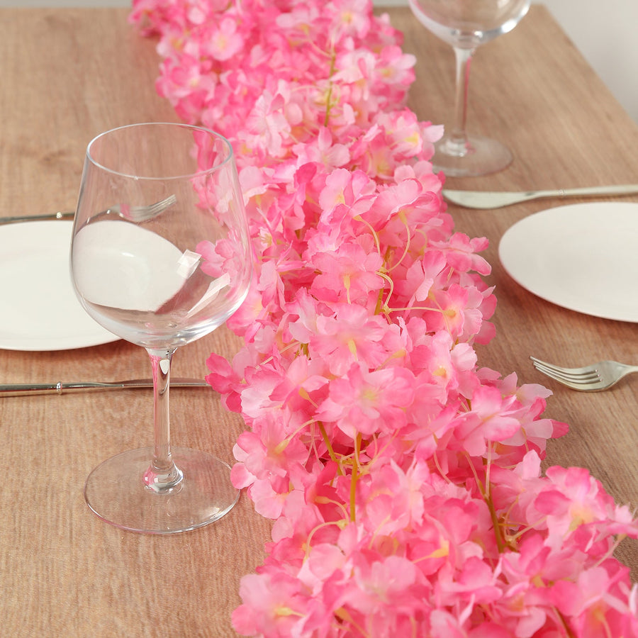 Pink floral table runner with glassware and plates set for dining.