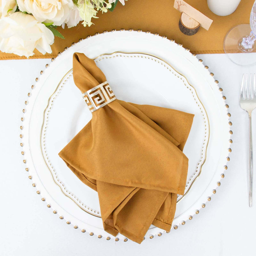 Brown napkin with decorative band on an elegant plate setting.