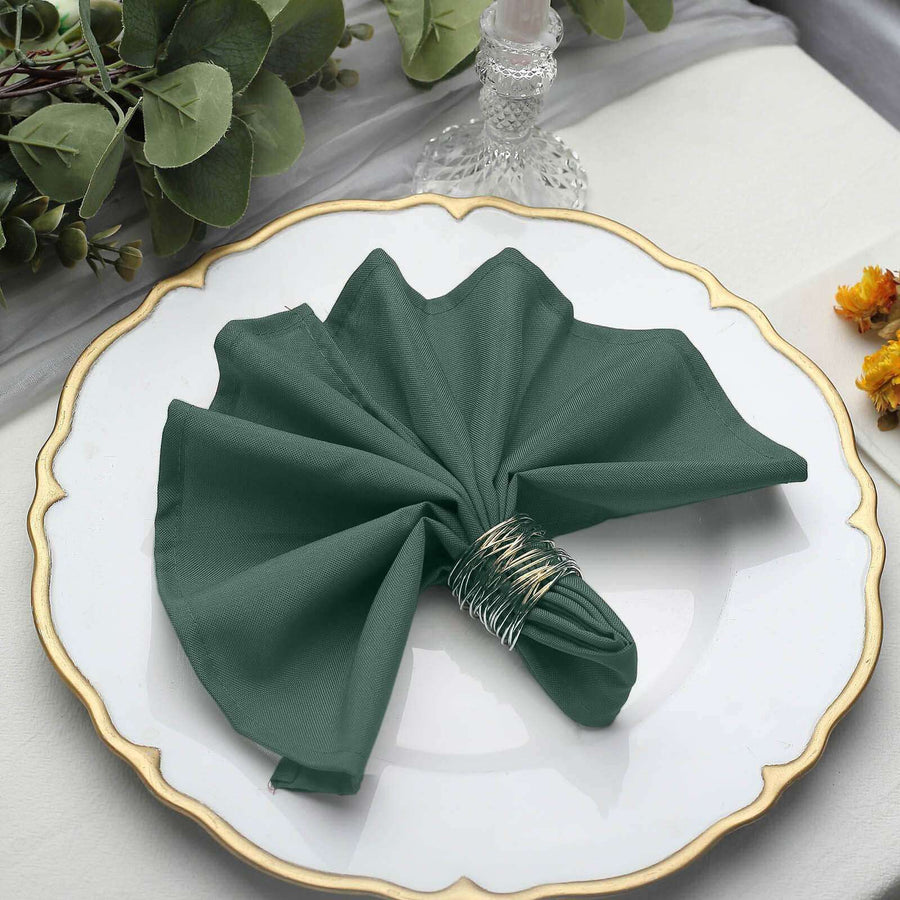 Green cloth napkin elegantly folded on a decorative plate.