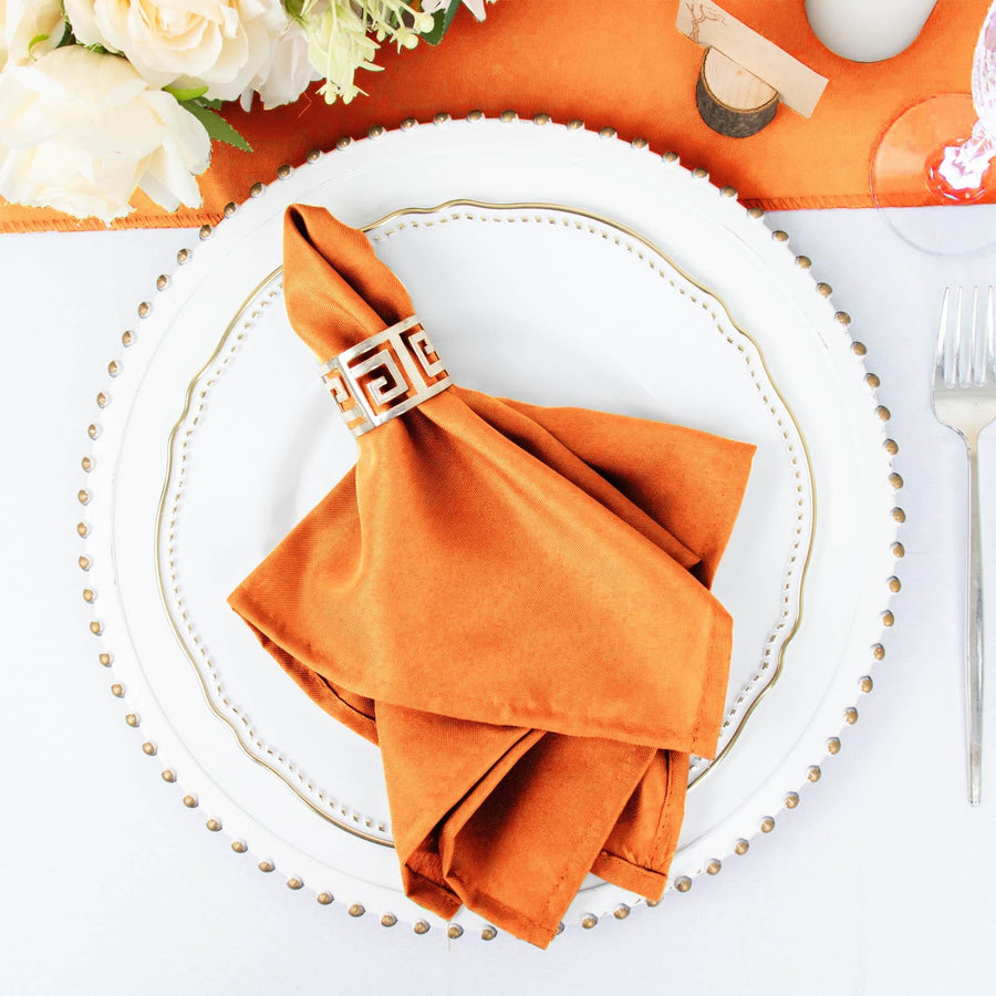 Orange napkin elegantly folded on a decorative white plate.