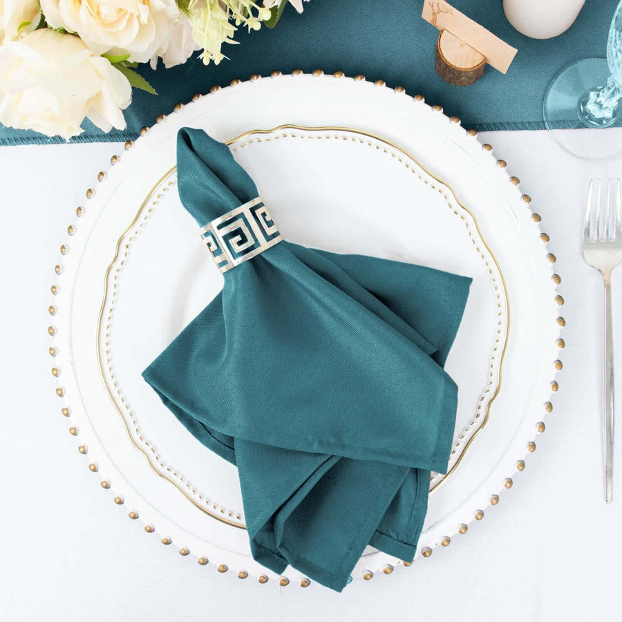 Teal napkin with decorative band on elegant dinner plate setting.