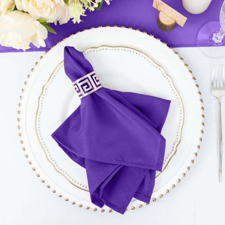 Purple napkin elegantly folded on a decorative plate with floral arrangement.