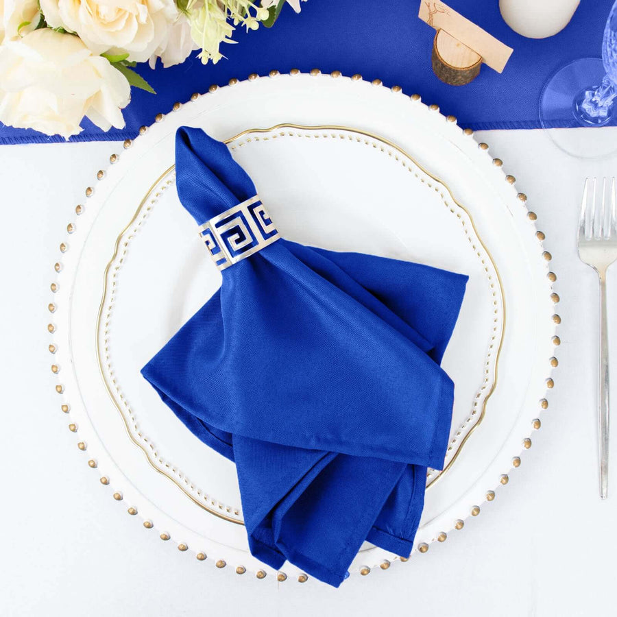 Blue napkin with geometric design on an elegant dinner plate setting.