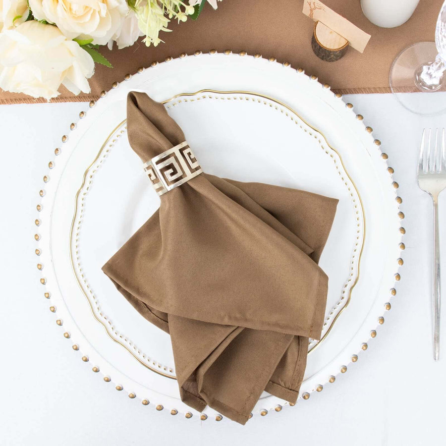 Brown napkin with decorative band on an elegant dinner plate.