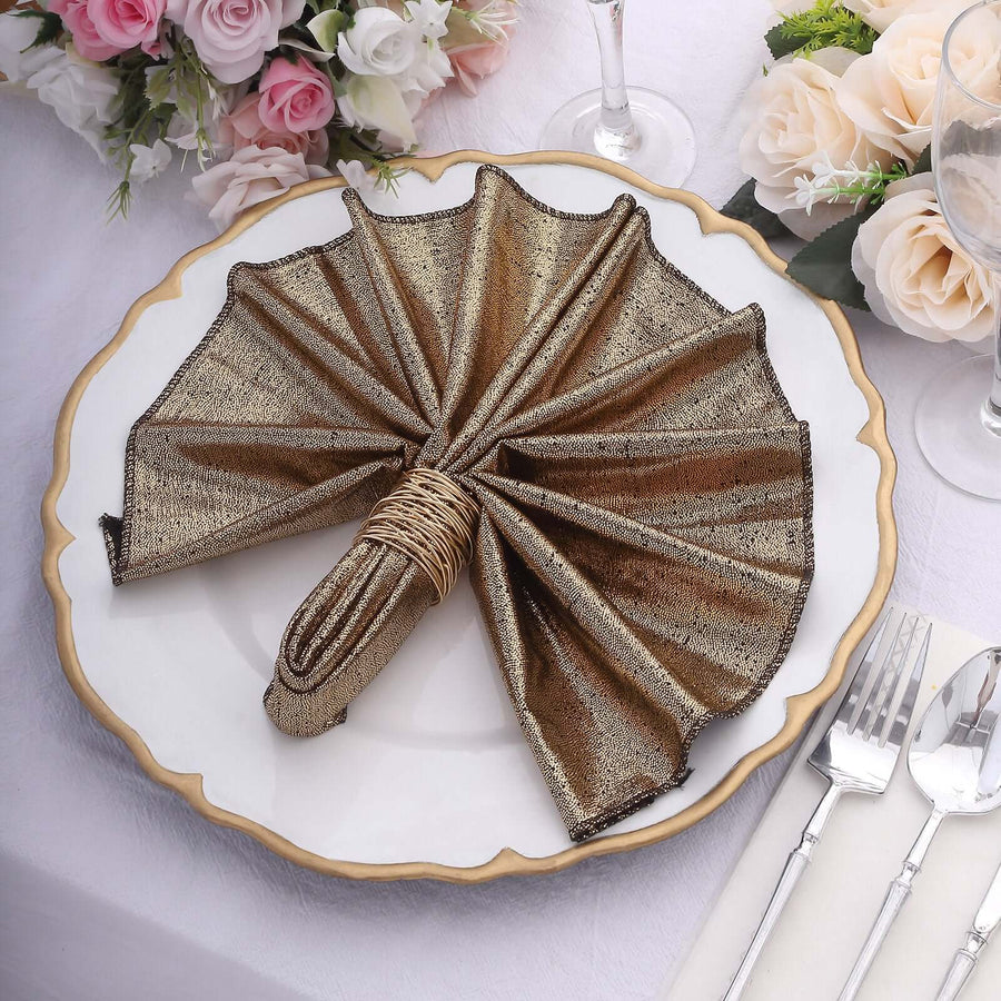 Elegant gold and bronze napkin folded in fan shape on a decorative plate.