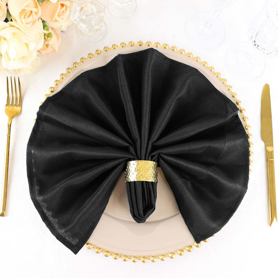 Elegant black napkin with gold ring on a decorative plate.