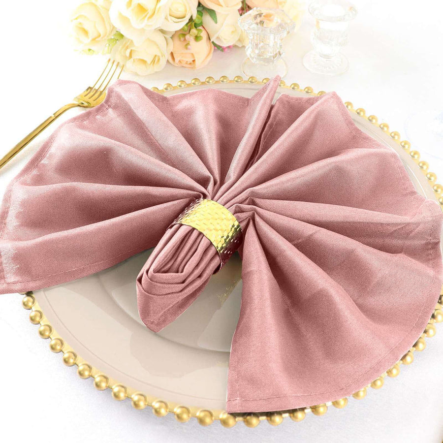 Elegant dusty rose napkin with gold ring on a decorative plate.