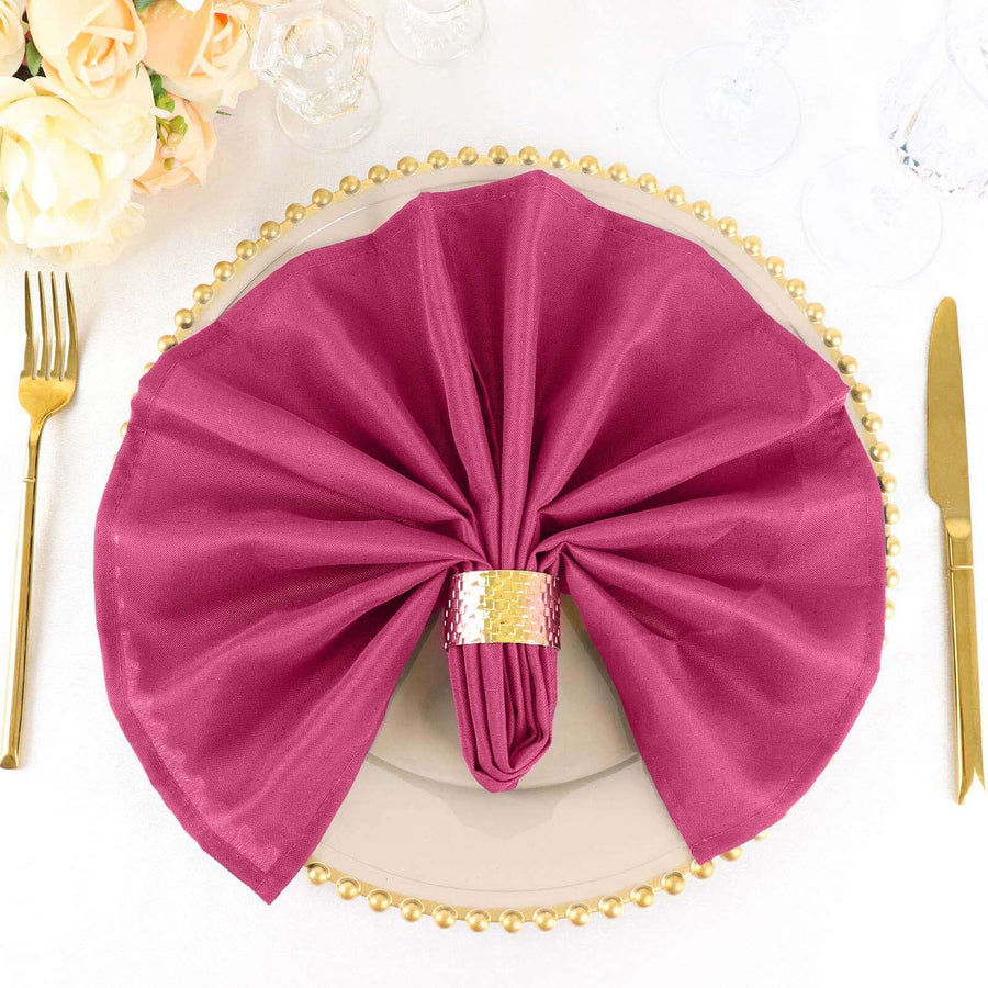 Elegant magenta napkin elegantly arranged on a gold plate with a decorative napkin ring.