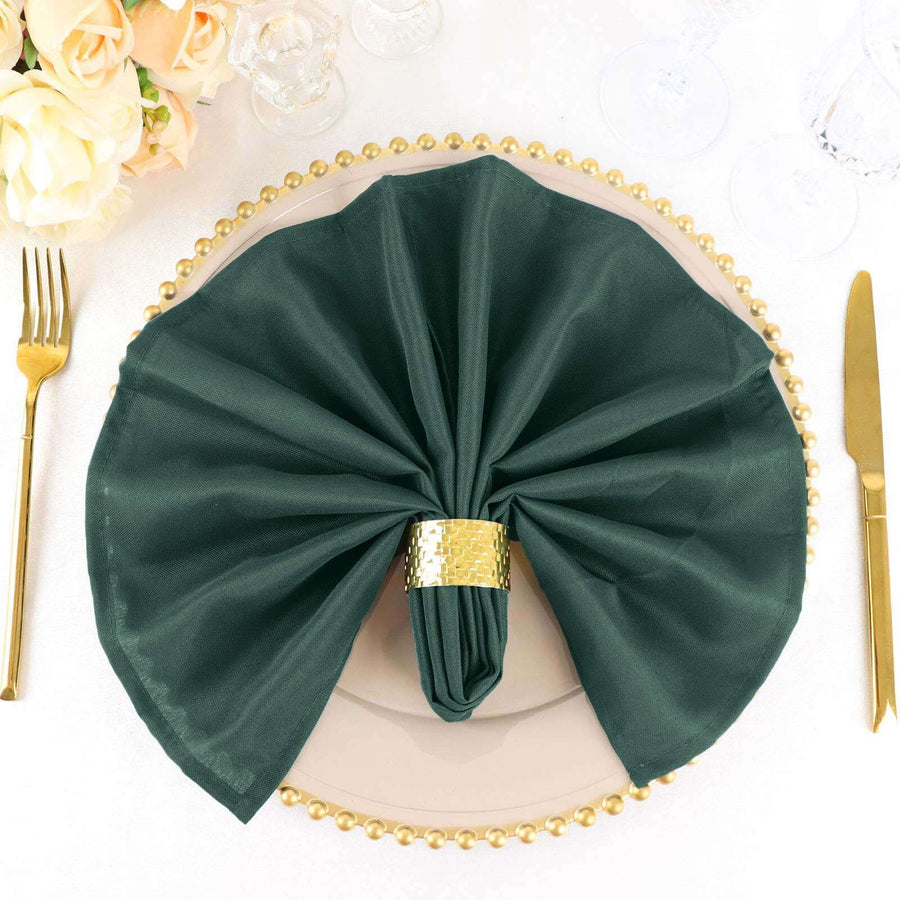 Elegant dark green napkin with gold ring on a decorative plate.