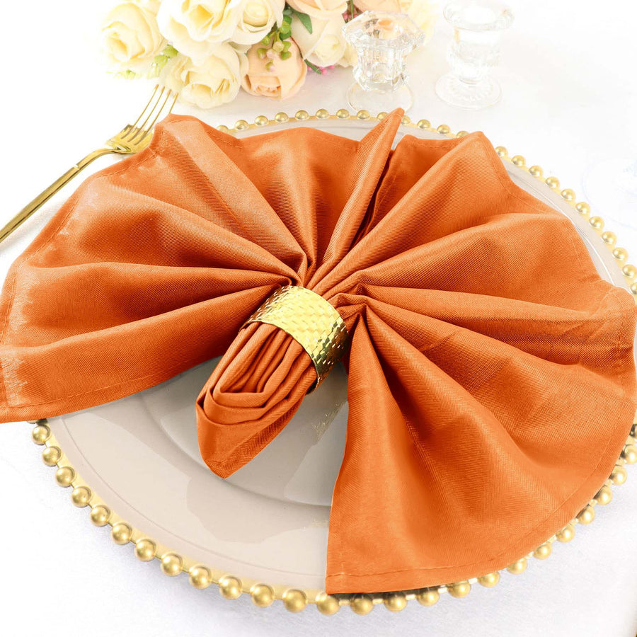 Elegant orange napkin with gold ring on a decorative plate.