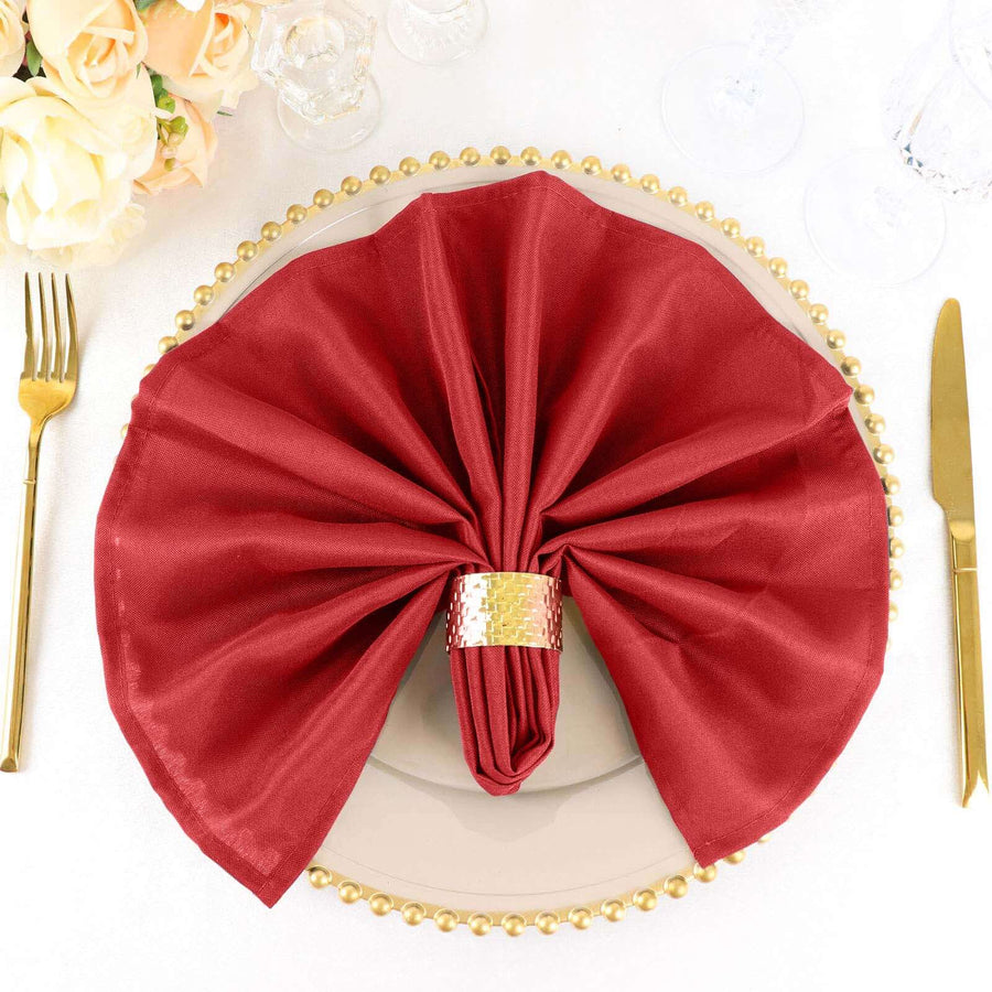 Elegant red napkin folded on a decorative plate with a gold napkin ring.