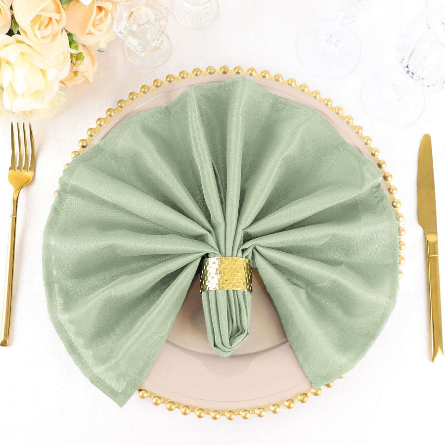 Green napkin elegantly arranged on a dinner plate with a gold napkin ring.