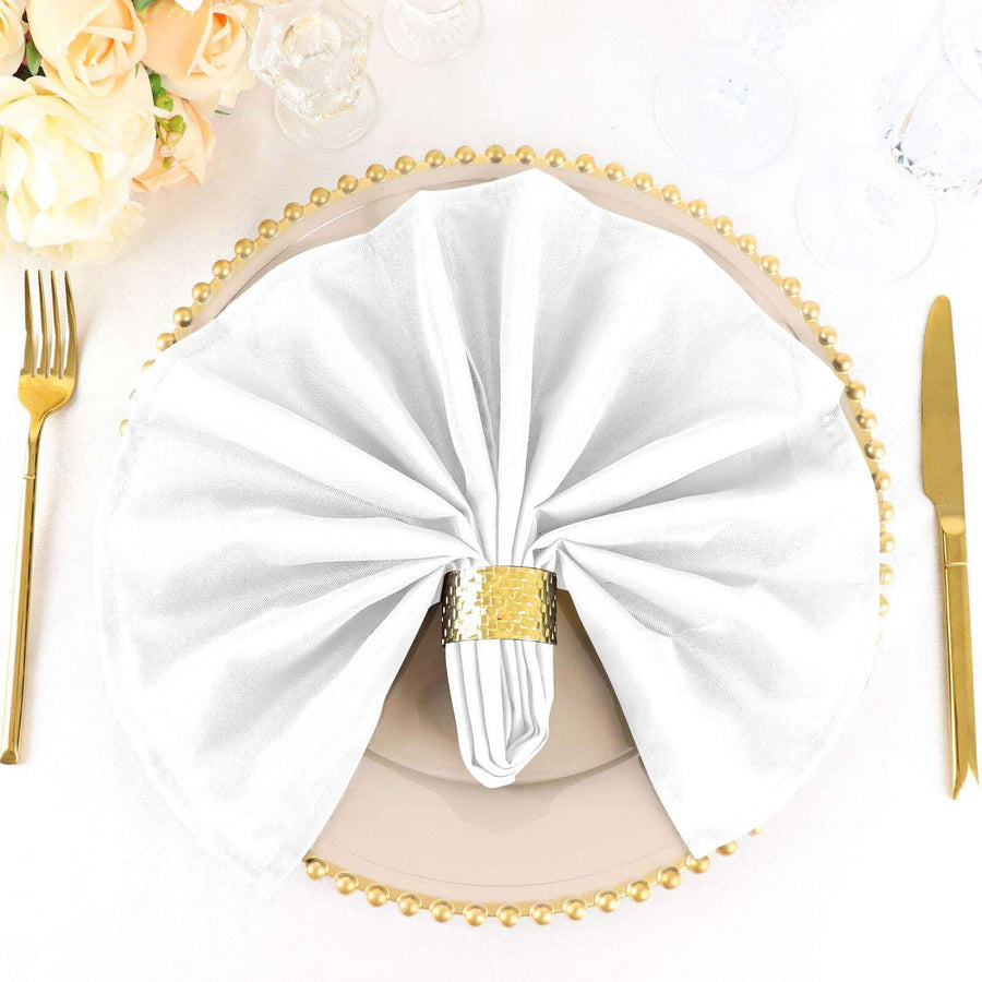 Elegant white napkin draped on a plate with a golden napkin ring.