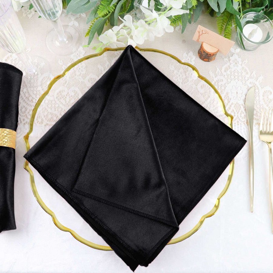Black satin napkin elegantly folded on a decorative plate.