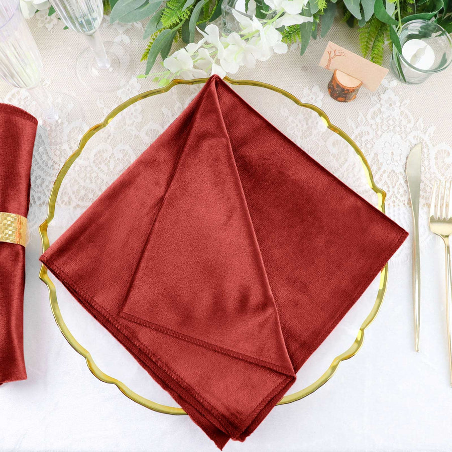 Burgundy satin napkin elegantly displayed on a gold plate.
