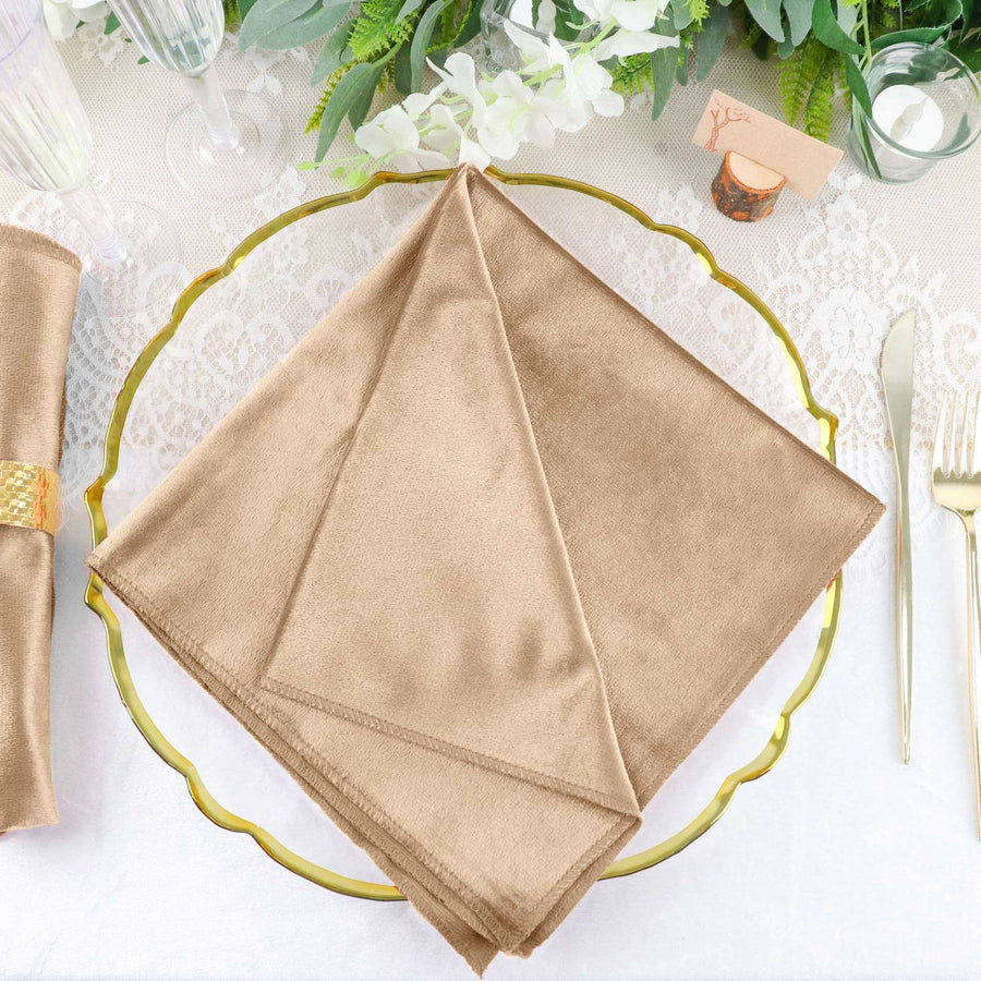 Elegant gold cloth napkin on decorative plate with greenery and table setting.