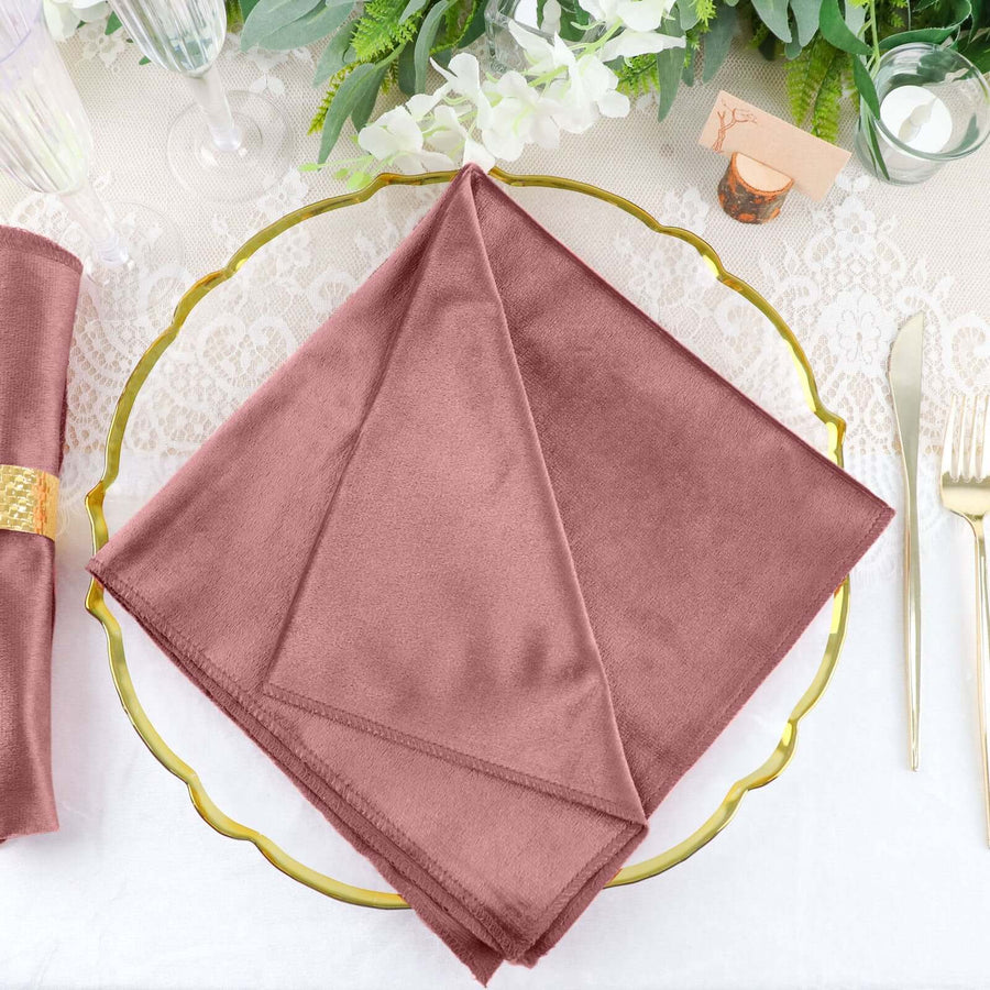 Rose-colored fabric napkin folded on a decorative gold plate.