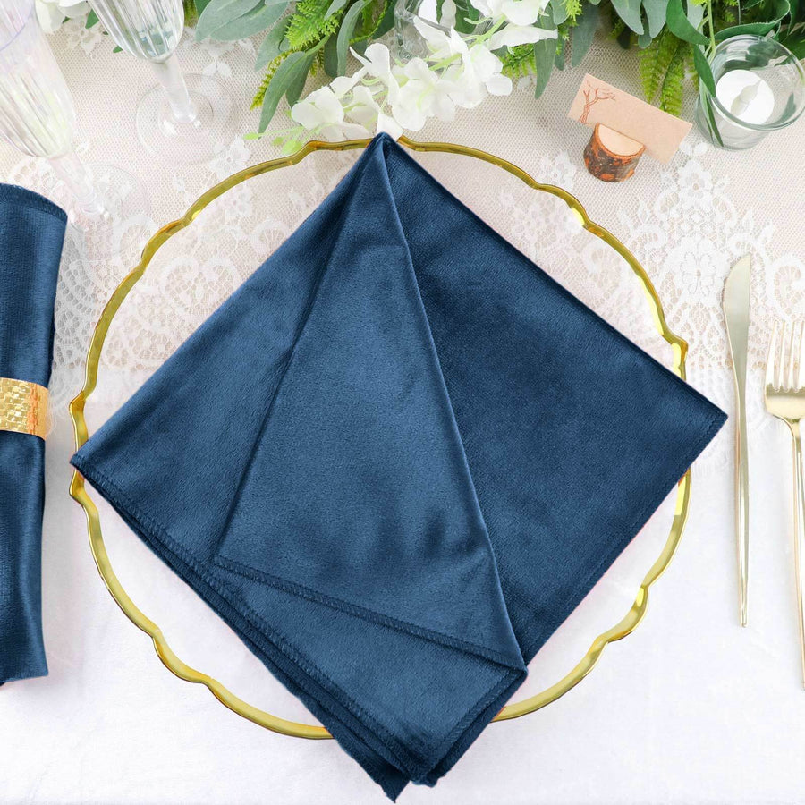 Navy blue satin napkin on a decorative gold plate.
