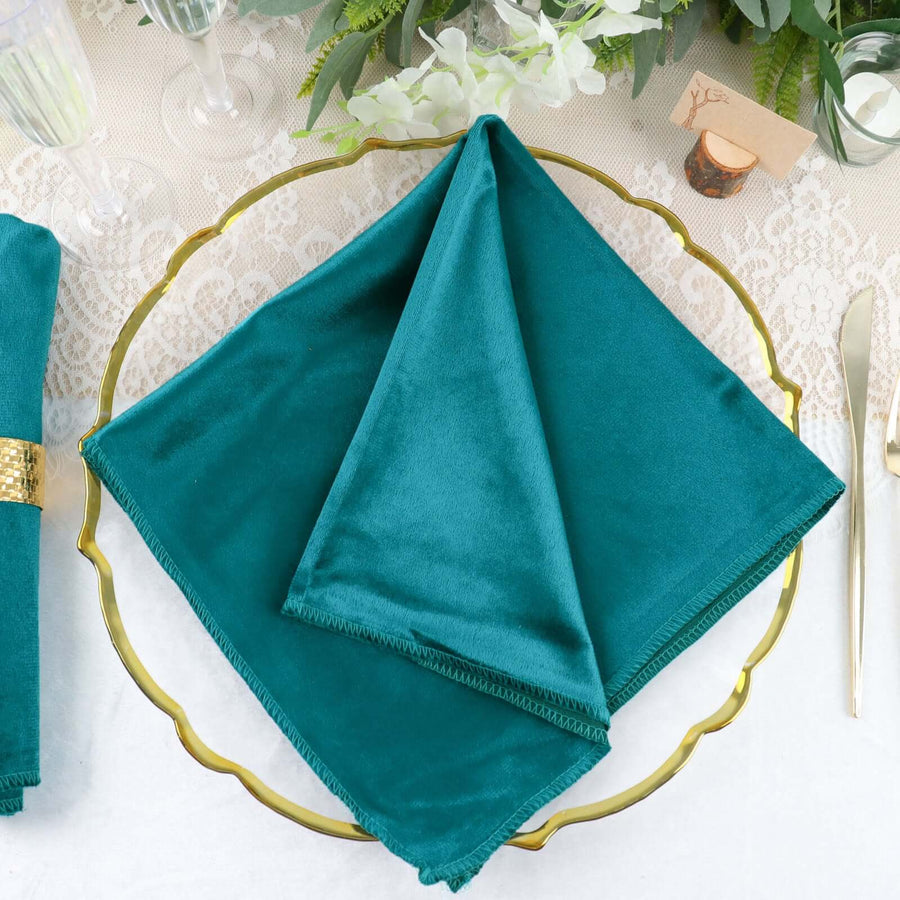 Teal velvet napkin elegantly folded on a gold plate.