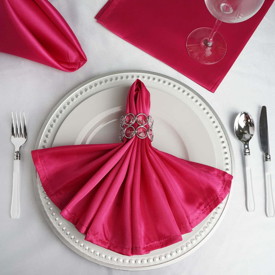 Pink satin napkin elegantly arranged on a white plate with silver cutlery.