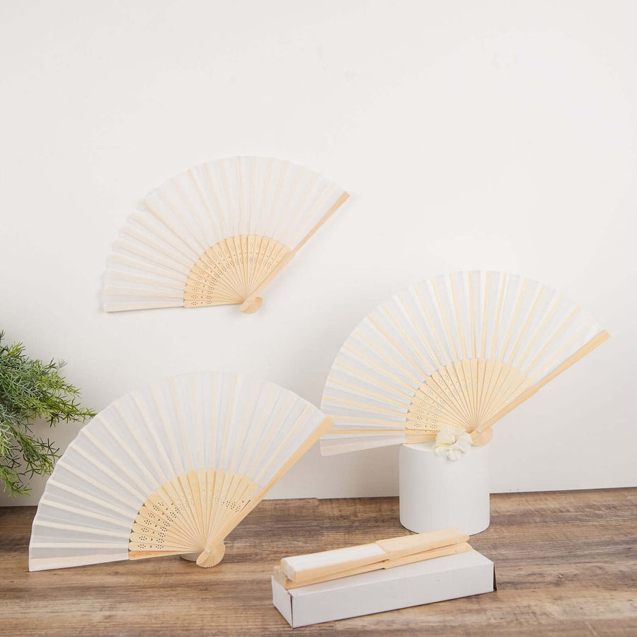 Three elegant folding fans with wooden handles on a neutral backdrop.