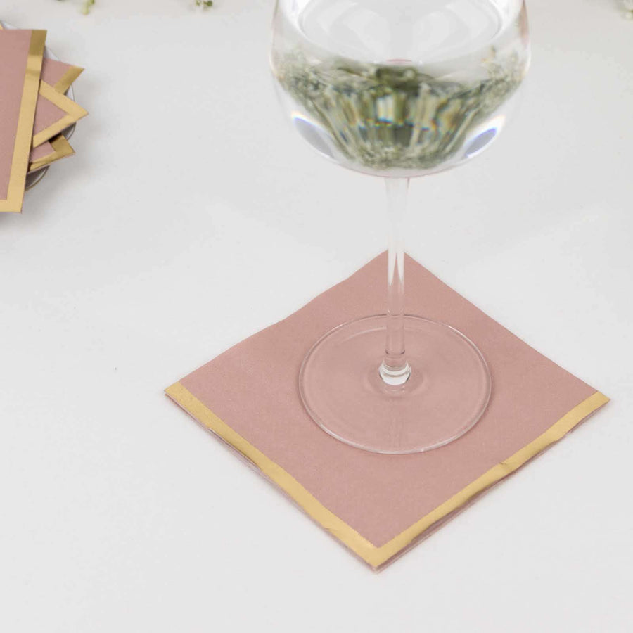 Pink napkin with gold trim under a glass, ideal for elegant dining.
