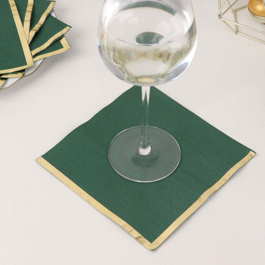 Green napkin with gold trim under a glass of water.