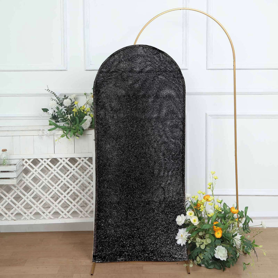 Black velvet arch backdrop with floral arrangement at the base.