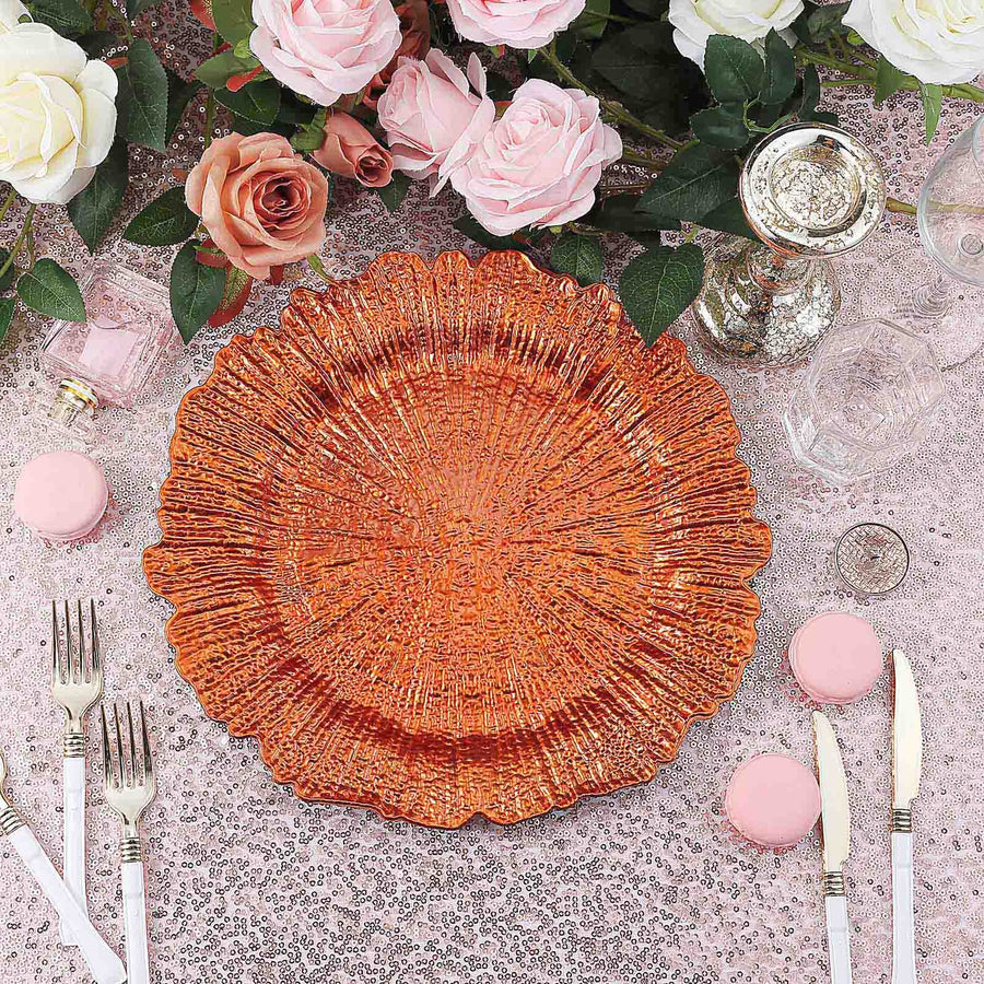Elegant orange decorative plate surrounded by flowers and table setting.