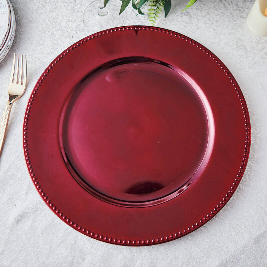 Burgundy decorative charger plate with beaded rim on a white tablecloth.