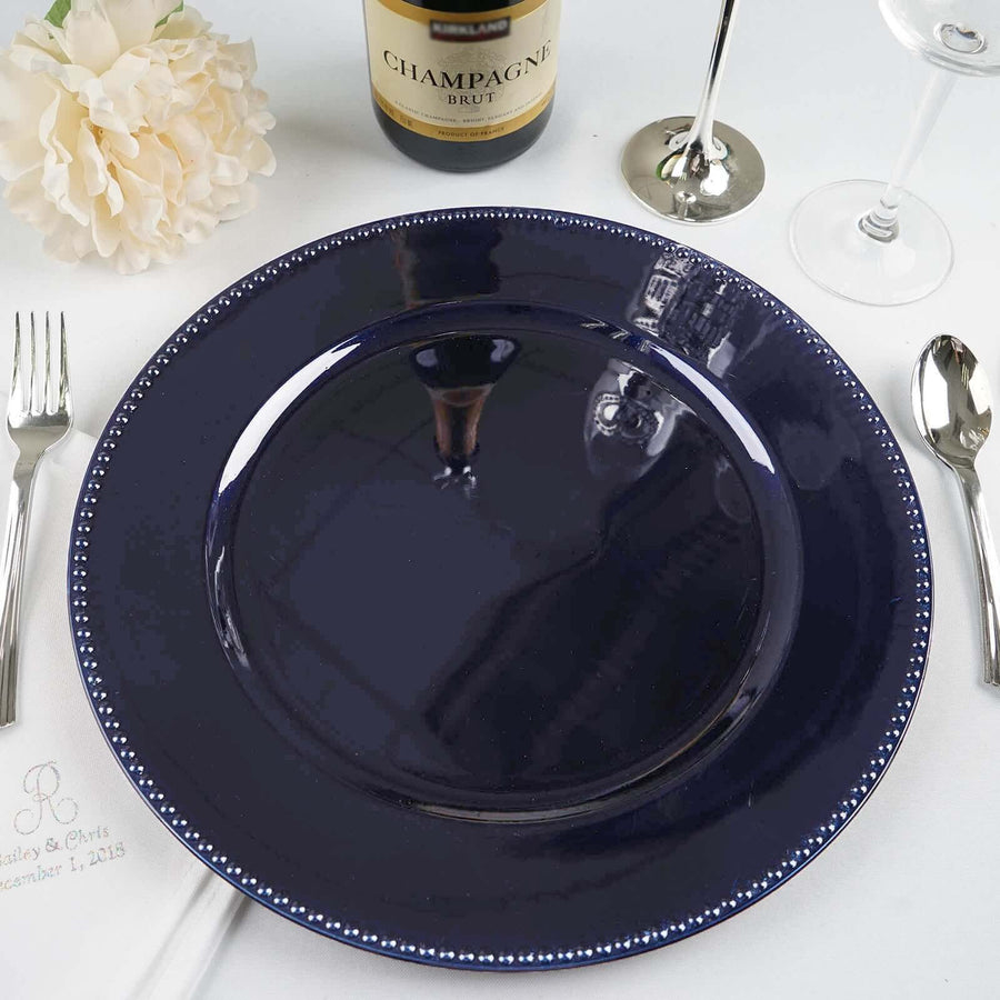 Navy blue dinner plate with silver beaded rim on a dining table setting.