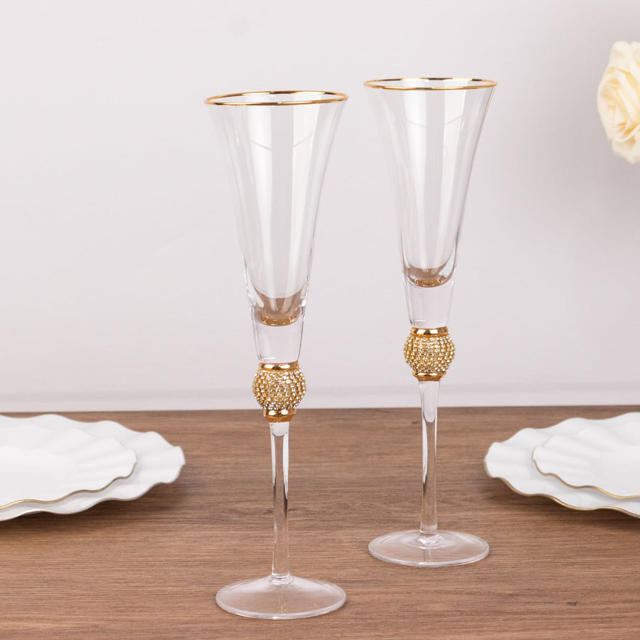 Elegant crystal champagne flutes with gold accents and decorative bases.