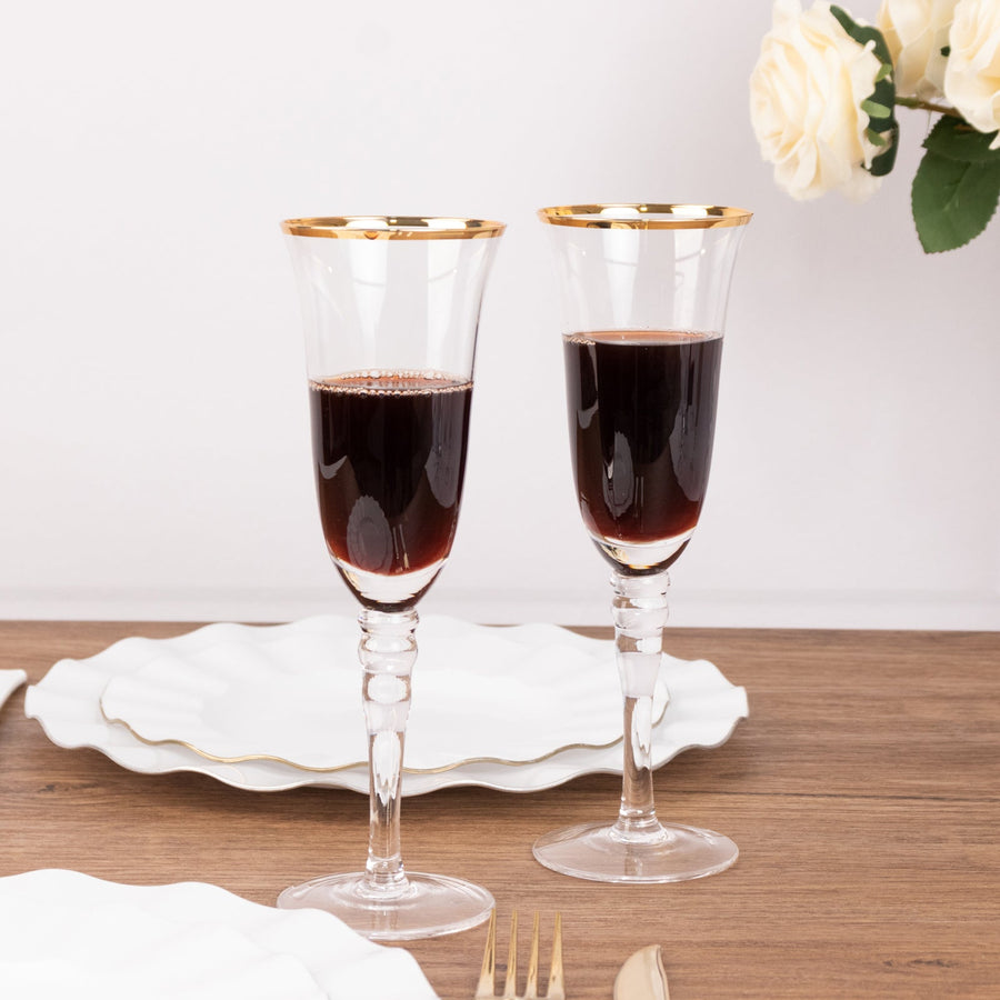 Elegant crystal wine glasses with gold rims filled with red wine.
