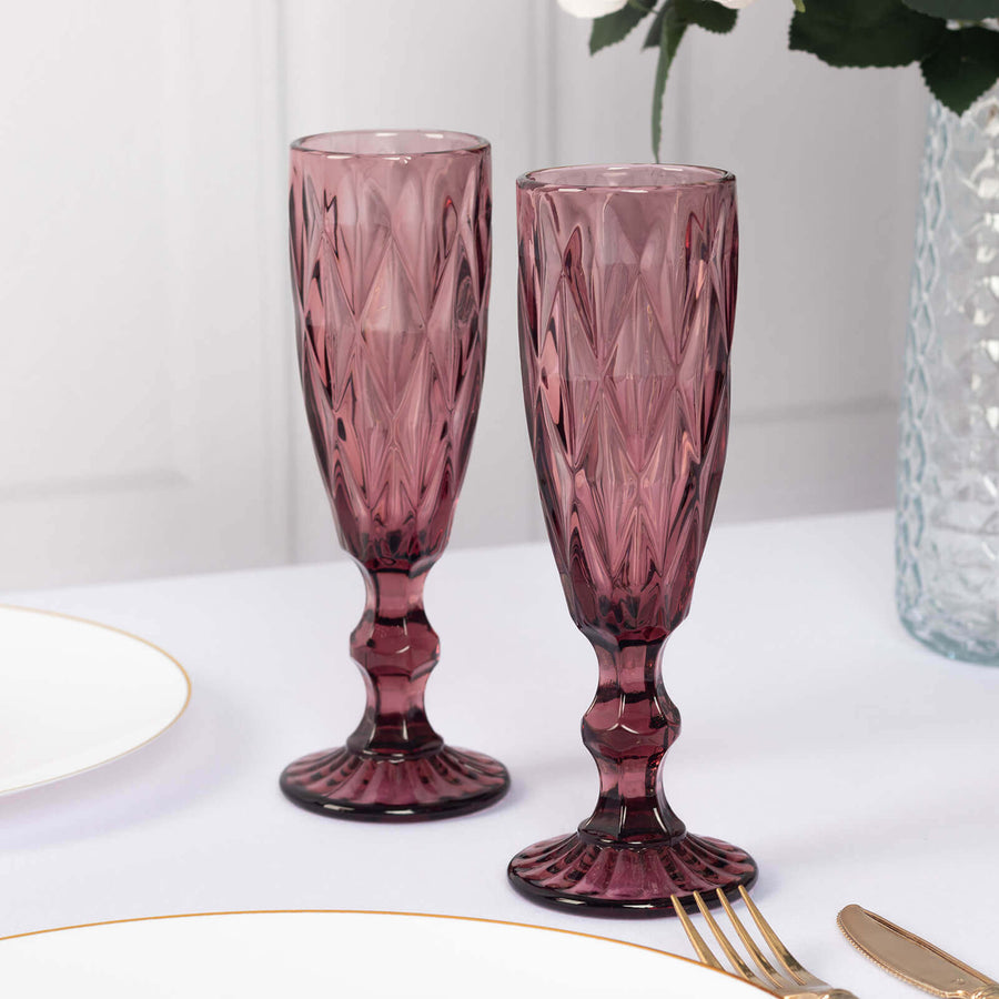 Elegant pink crystal champagne flutes on a dining table.