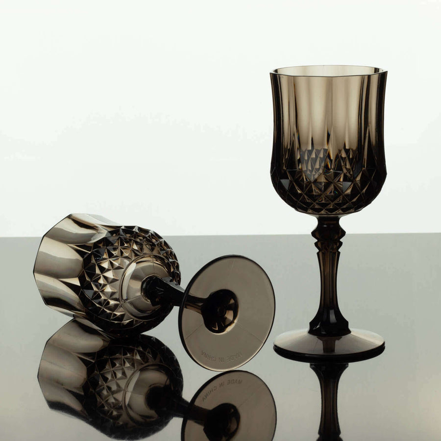 Elegant smoke glass goblet and matching tumbler on reflective surface.