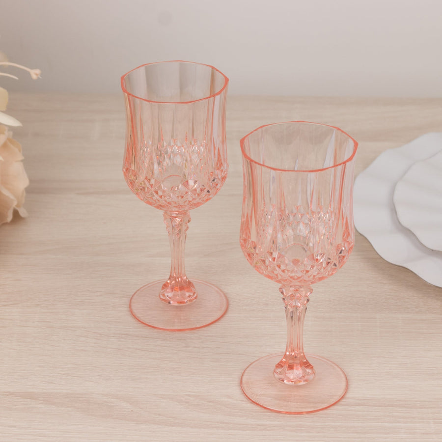 Pair of elegant coral crystal goblets on a wooden surface.