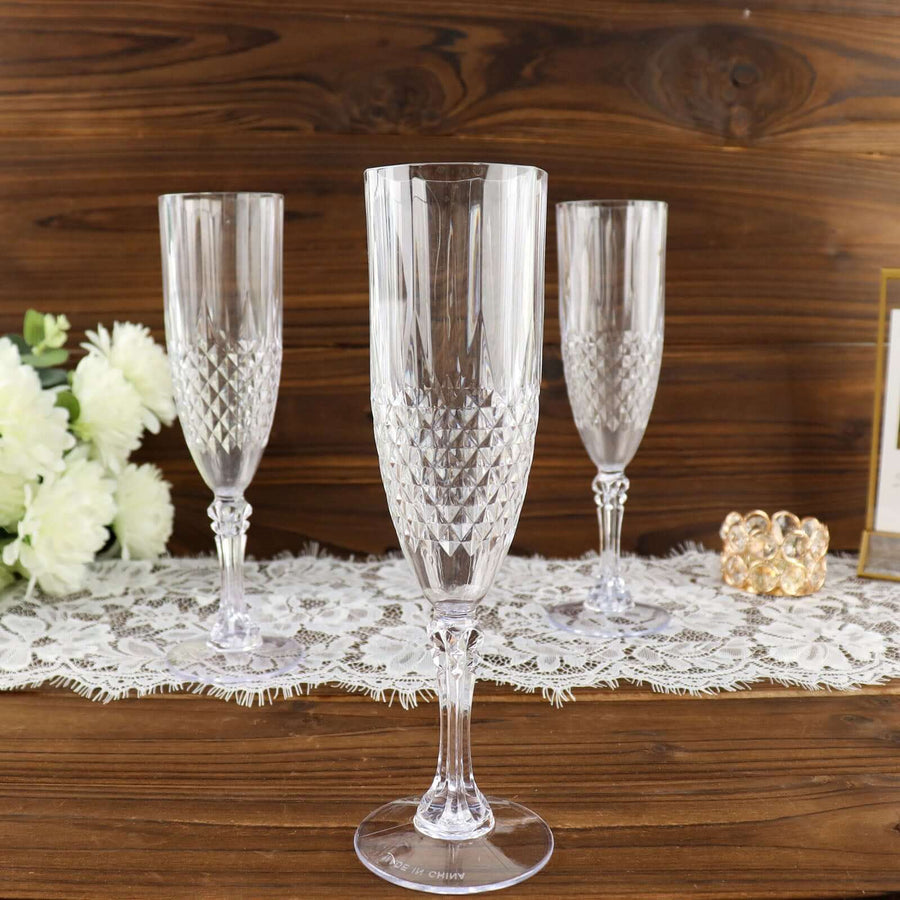 Elegant crystal champagne flutes set on a lace table runner against a wooden backdrop.