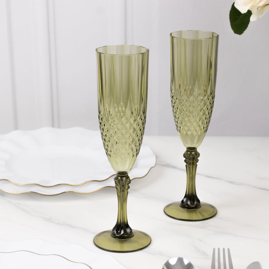 Pair of elegant green champagne flutes on a marble table.
